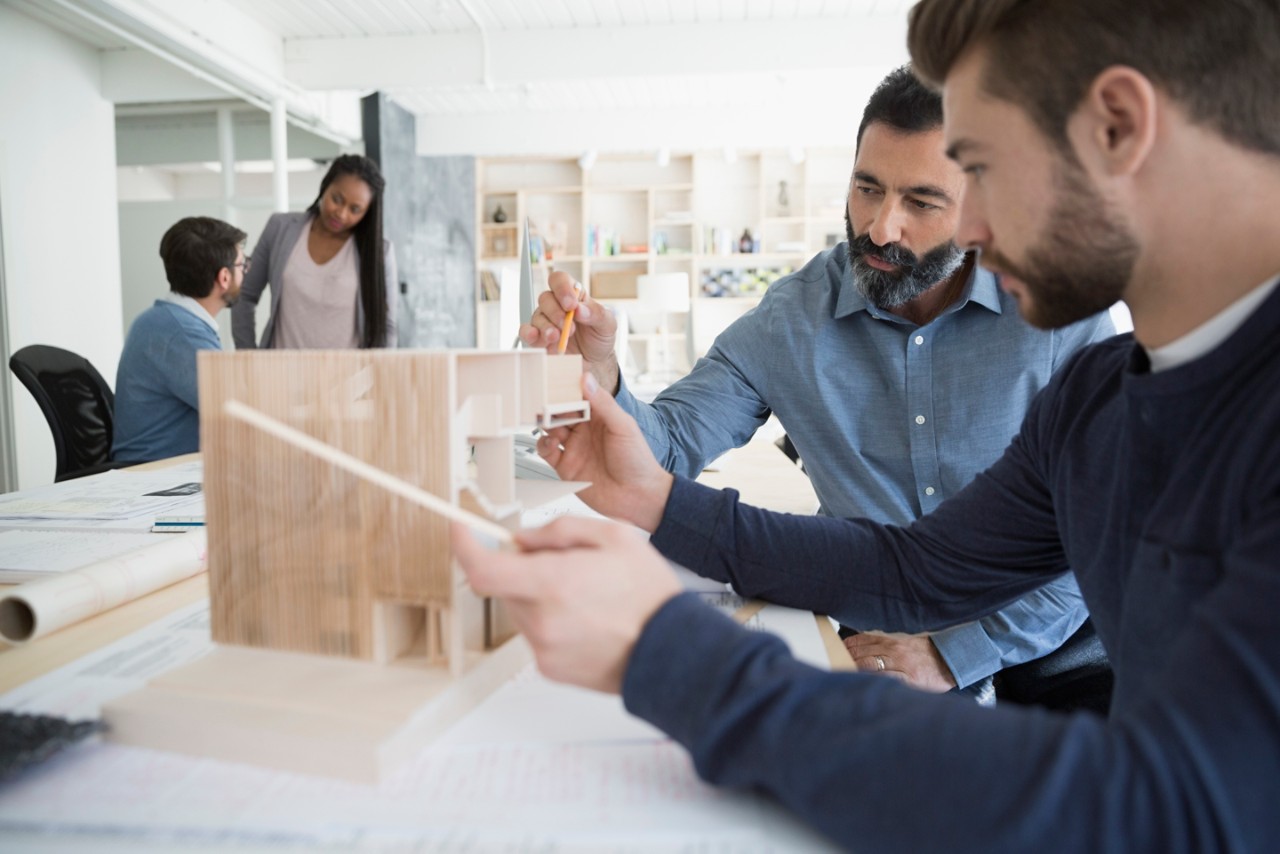 Male architects assembling architectural model in office