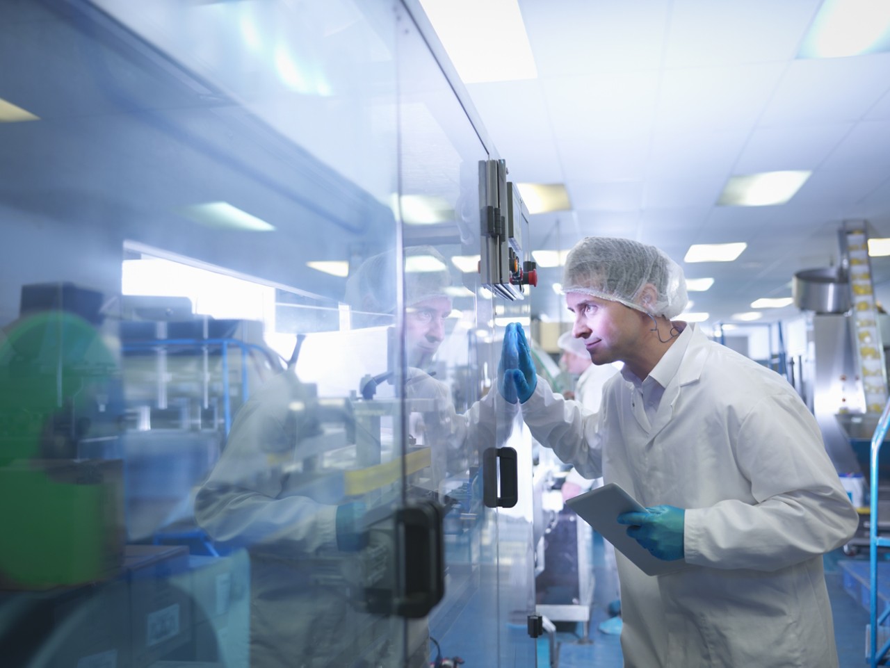 Worker inspecting tablets as they are put into packaging in pharmaceutical factory