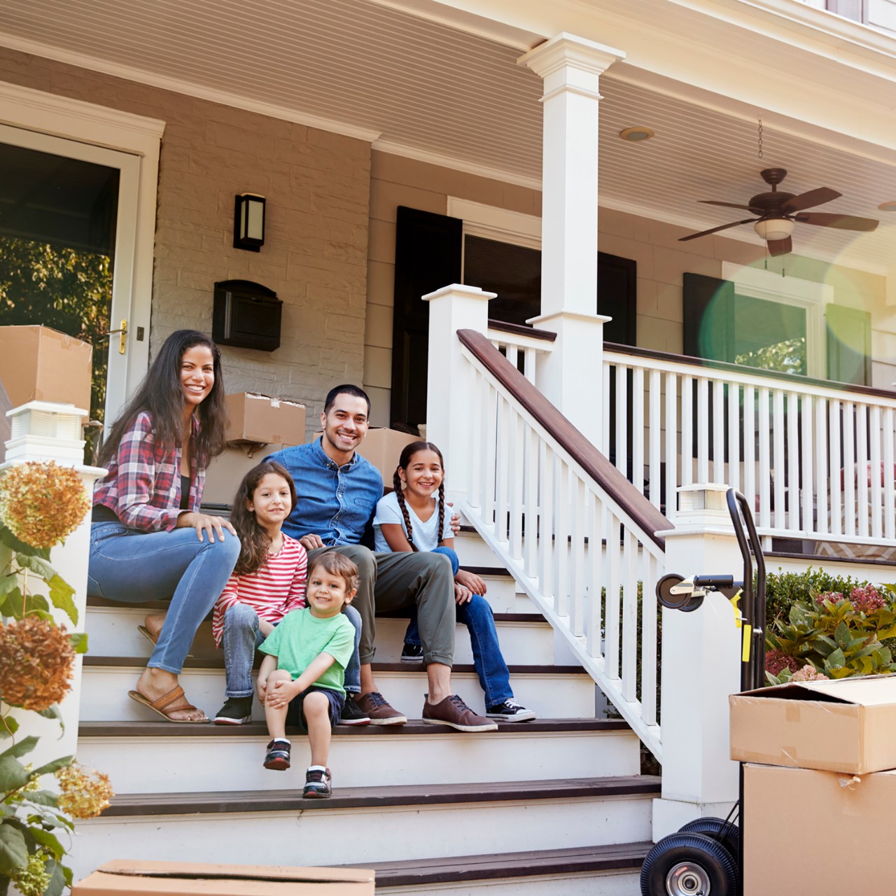 Family Sitting On Steps Of New Home On Moving In Day