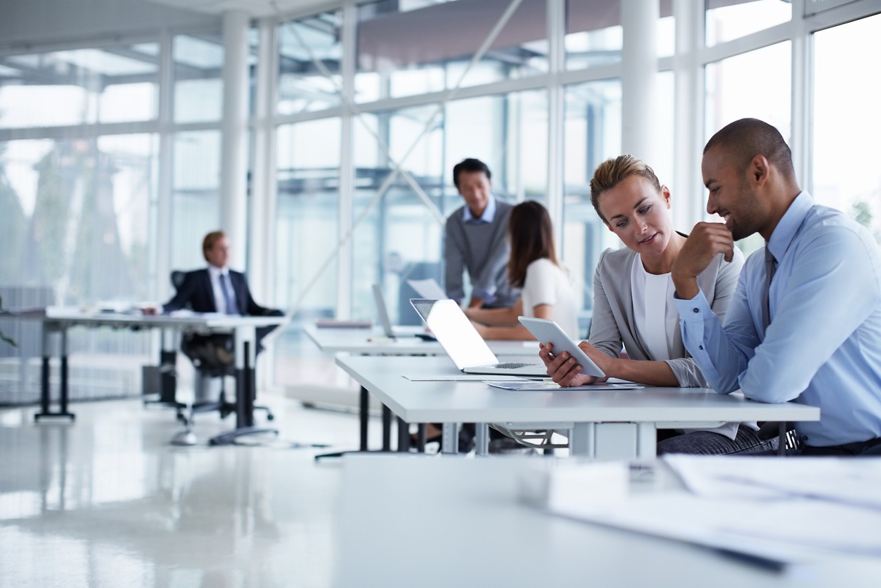 Colleagues at table discussing over tablet