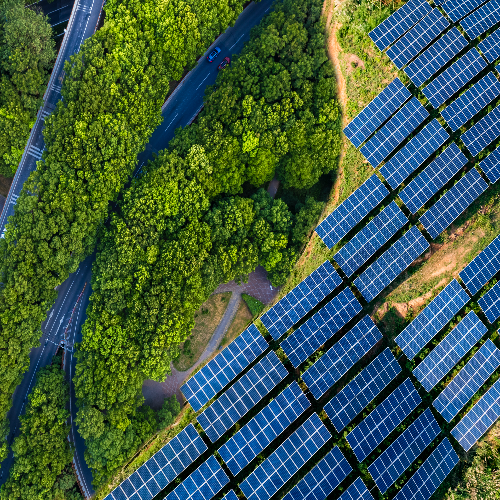 Aerial view of roads green trees and field of solar panels