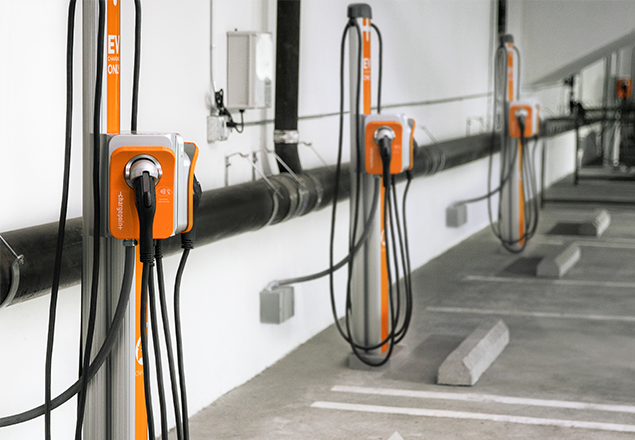 Woman using Eaton Green Motion Building charger at office building. Woman using Eaton Green Motion Building charger at an office building. Eaton commercial EV charging infrastructure solutions. 