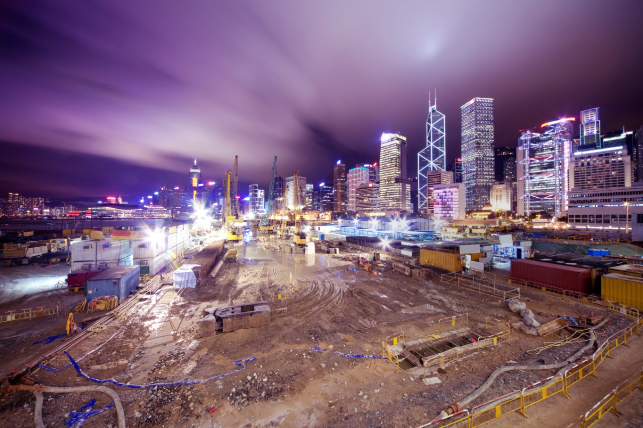 Construction with brightly lit buildings in the background