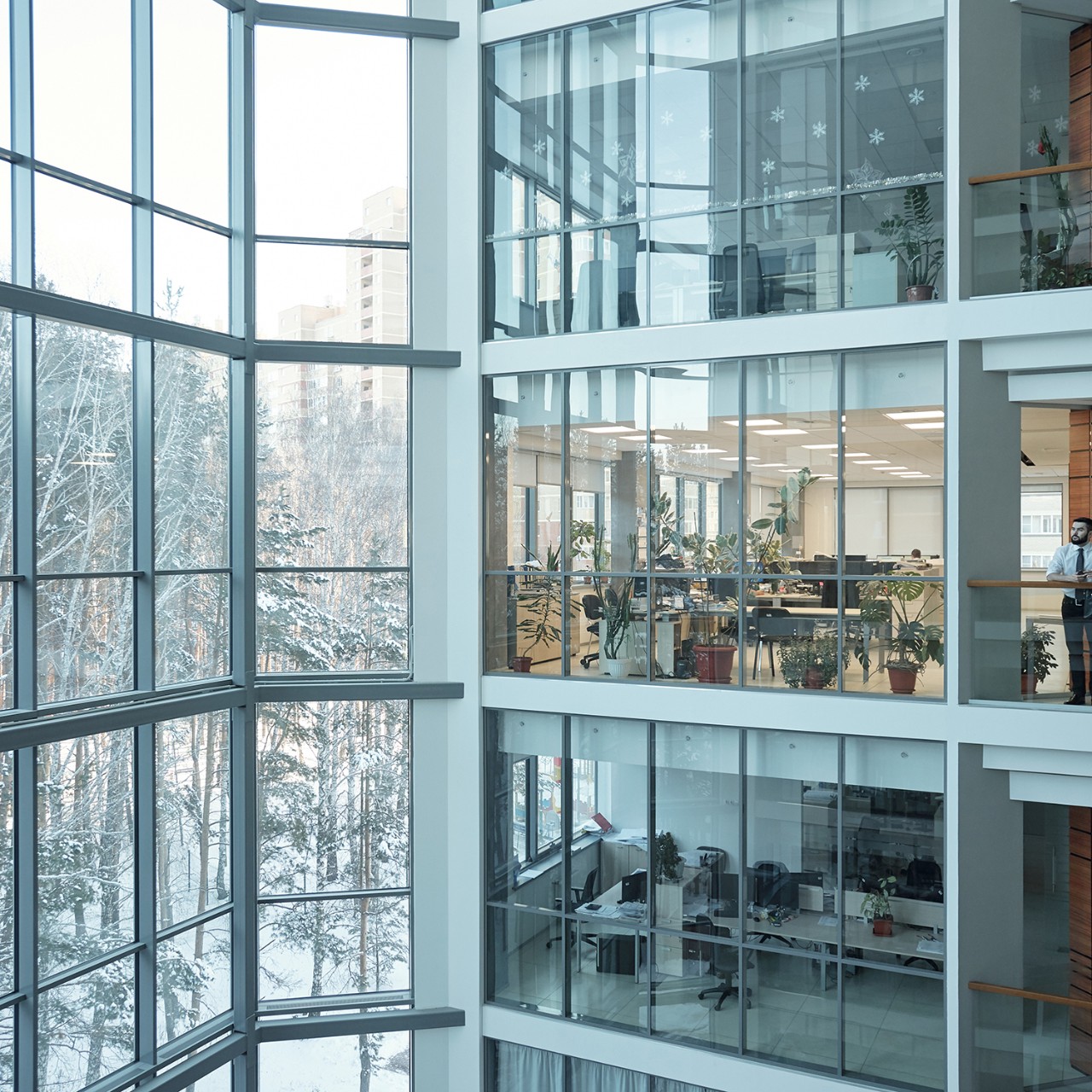 Interior of contemporary multi-floor business center with large windows and many offices in front of them