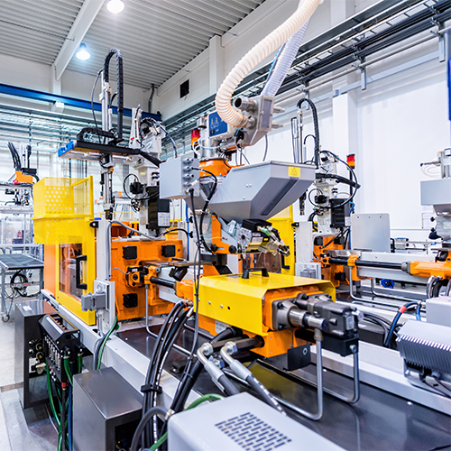 Horizontal color image of large group of automated injection moulding machines for plastic parts production. Powerful molding machinery in factory arranged in a row.