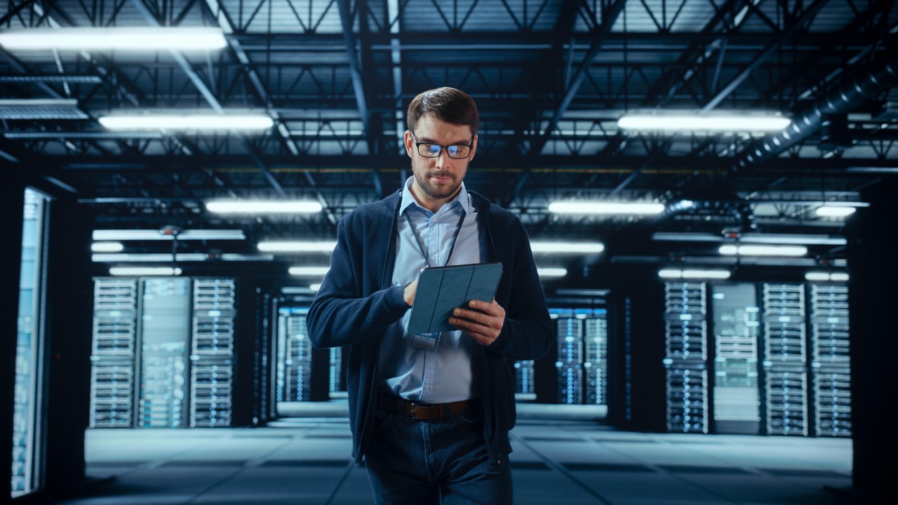 male-it-specialist-walks-between-row-of-operational 1394184402